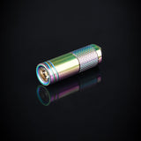 A titanium alloy mini flashlight with a multicolored rainbow coating, attached to a metal chain, displayed on a textured grey background.