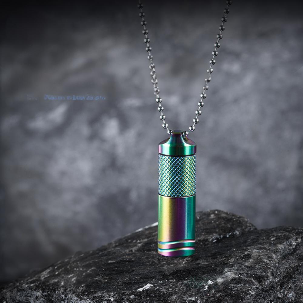 A titanium alloy mini flashlight with a multicolored rainbow coating, attached to a metal chain, displayed on a textured grey background.