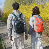 Two people walking outdoors with backpacks, surrounded by yellow flowers and greenery.